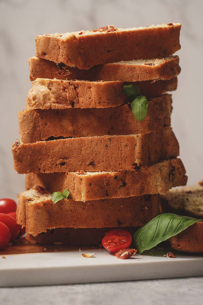 stacked slices of tomato basil bread with a fresh basil garnish